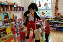 Dzieci w kolorowej sali przybijają piątkę z myszką Miki.