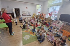 W-sali-przedszkolnej-dzieci-zgromadzone-na-dywanie-sluchaja-przemowy-Pani-Wicedyrektor.