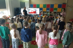 Dzieci stoją na baczność i śpiewają hymn narodowy.