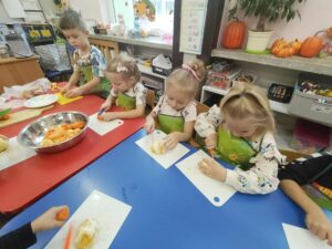 Dzieci z grupy Zajączki samodzielnie przygotowują owoce i warzywa do przyrząrzenia soku. Kroją je na mniejsze kawałki. Używają specjalnych noży i desek.