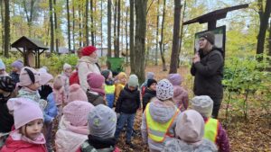 Pani leśnik opowiada ciekawostki ze świata roślin i zwierząt grupie dzieci. 