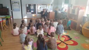 Dzieci siedzą na kolorowym dywanie. Przed nimi na krześle siedzi Pan z Kozienickiego Parku Krajobrazowego. Dzieci słuchają wykładu na temat życia jeża.