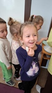 Usmiecjhnięta dziewczynka pokazuje zagipsowany palec.