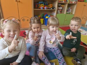 Grupka dzieci demonstruje zagipsowane palce, są wesołe i i uśmiechnięte.