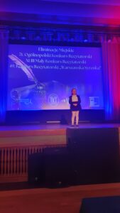 Hanna Sałata rezytuje wiersz na scenie. W tle slajd z informacją o konkurskie.