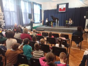 Uczennica szkoły Muzycznej gra na fortepianie utwór muzyki klasycznej. Widzowie słuchają z zapartym tchem.