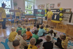 Dzieci siedzą na dywanie i słuchają opowieści Pszczelarzy.